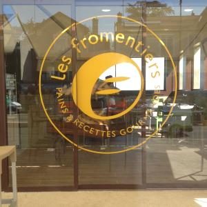 Adhésif doré Les Fromentiers appliqué sur la vitrine d'une boulangerie