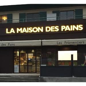 Enseigne rétroéclairée La Maison des Pains vue de nuit, lettres blanches lumineuses