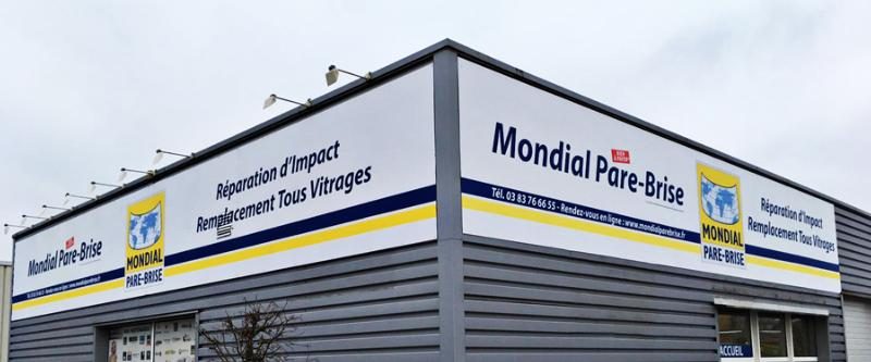 Enseigne Mondial Pare-Brise et panneaux d'information sur la façade d'un centre auto