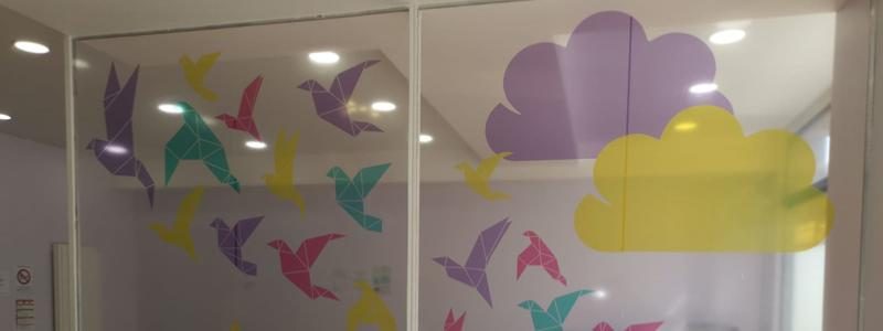 Décor adhésif nuages et oiseaux sur les vitrages d'un espace d'accueil pour enfants
