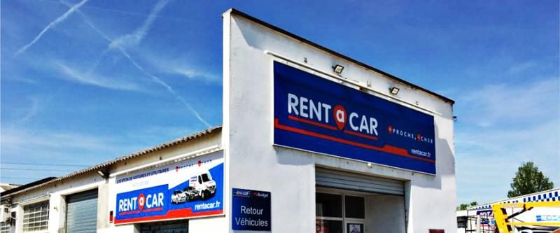 Enseigne lumineuse Rent A Car en bandeau sur la façade d'une agence de location de véhicules